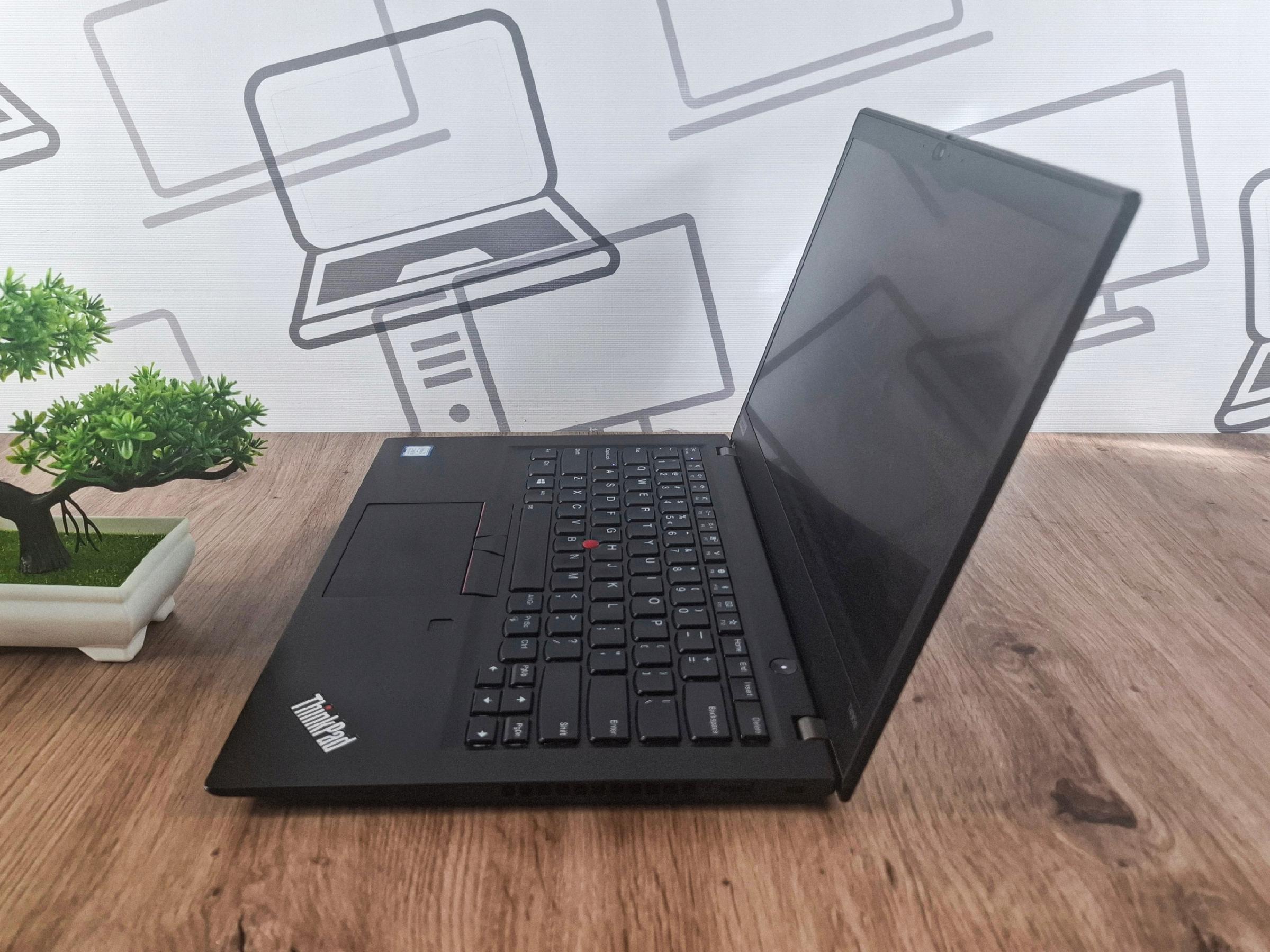 Otwarty laptop Lenovo ThinkPad T490s pod kątem z boku, widoczna klawiatura z czerwonym TrackPointem i wygaszony ekran.
