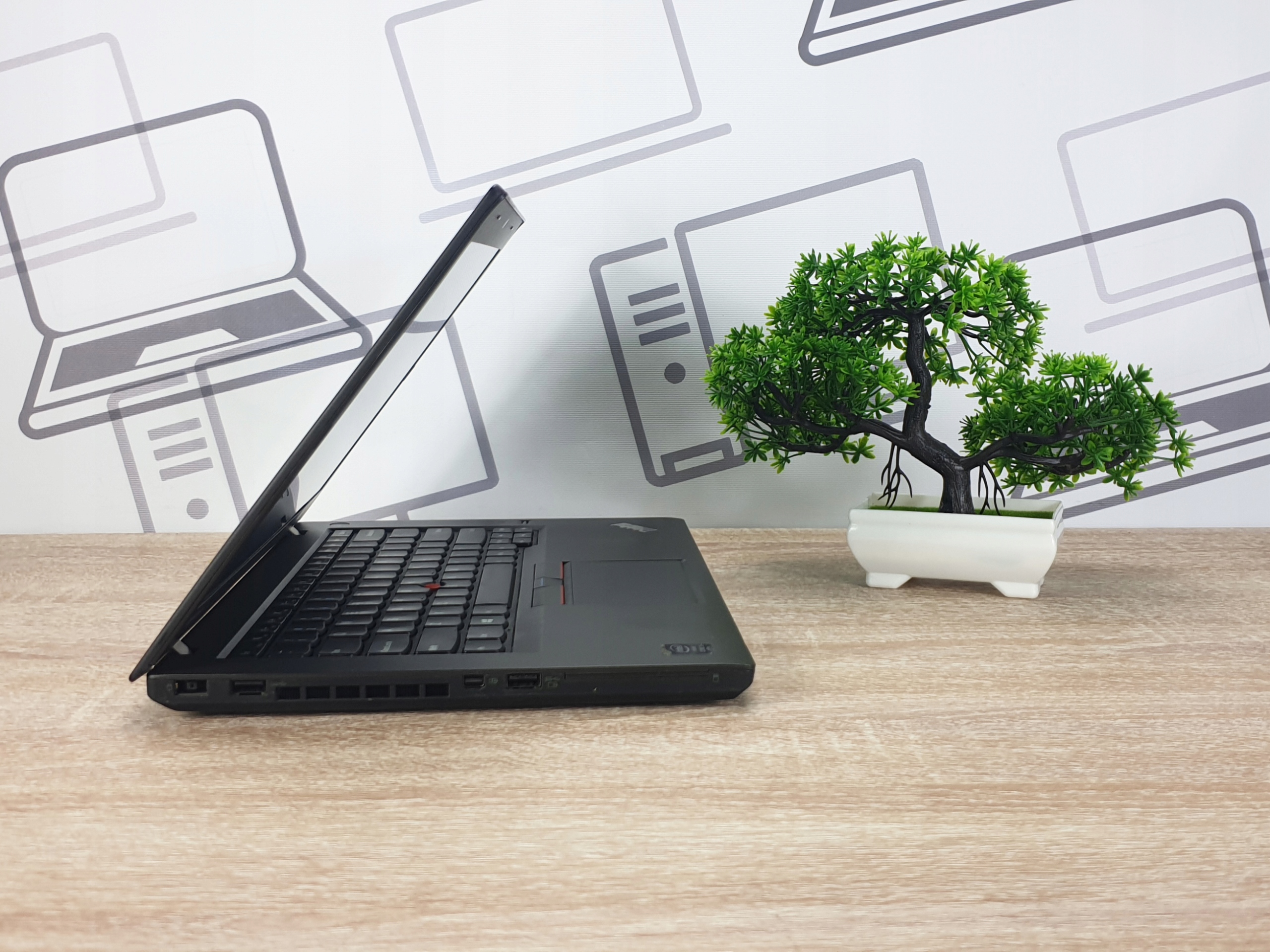 Laptop Lenovo ThinkPad widziany z boku, uchylony pod niewielkim kątem, obudowa czarna matowa.