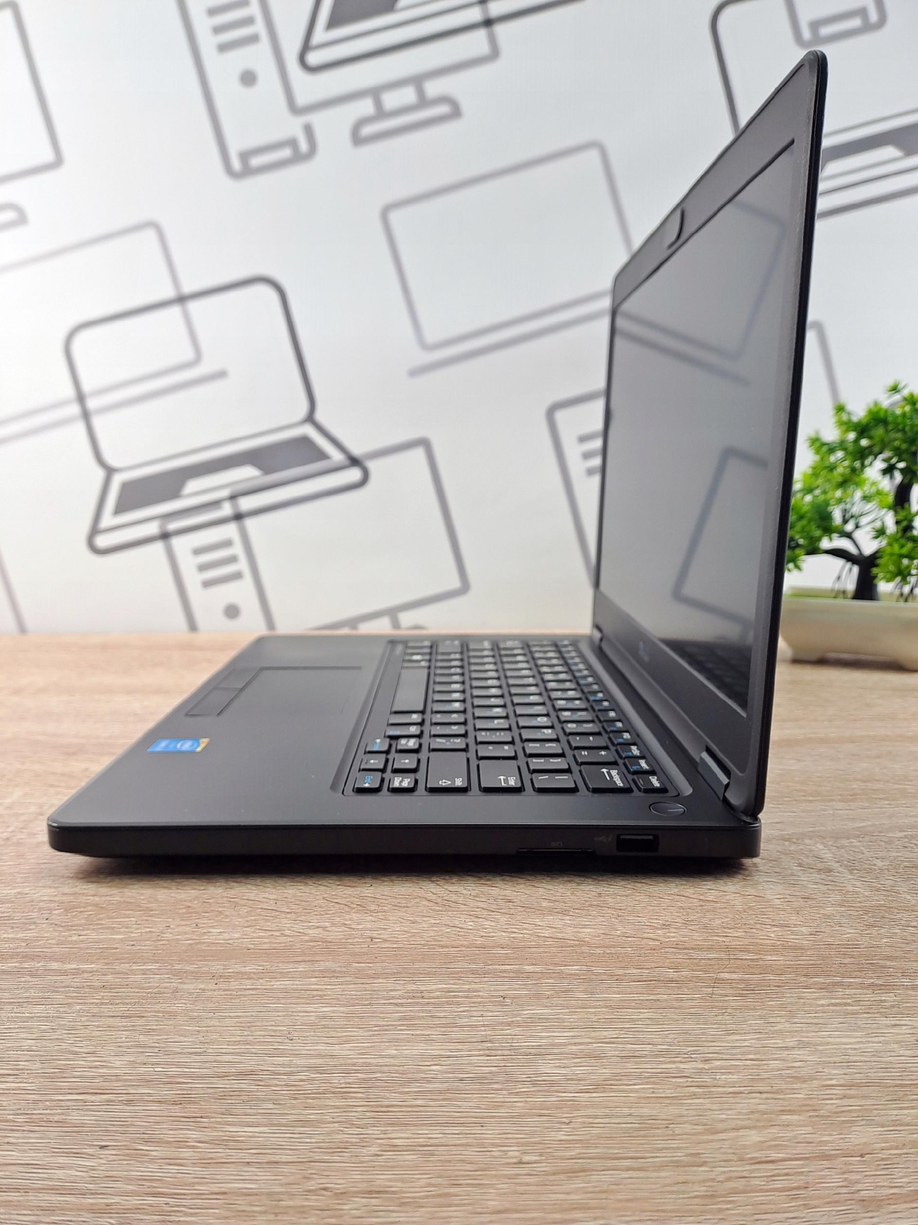 Laptop Dell Latitude widziany z boku pod kątem, ekran uchylony, widoczna klawiatura i port z prawej strony obudowy.