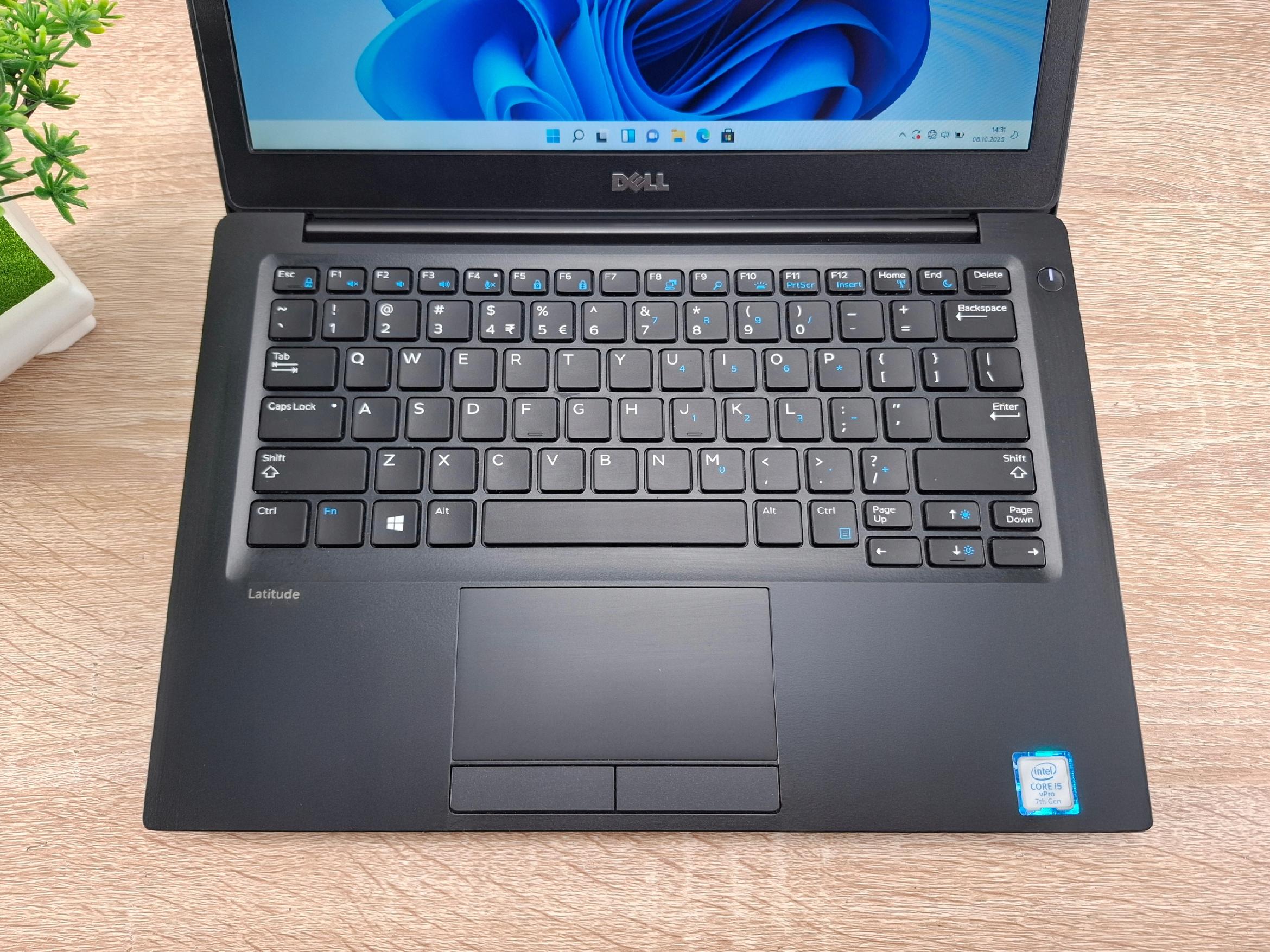 Otwarty laptop Dell Latitude 7280 widziany z góry, ekran z logo Dell, klawiatura i touchpad na jasnym drewnianym blacie.