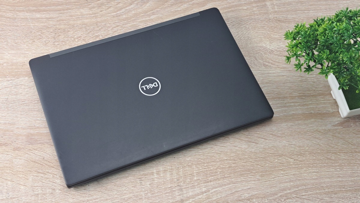 Zamknięty laptop Dell z widoczną klapą matowej czarnej obudowy i logo Dell na środku, ujęcie z góry.