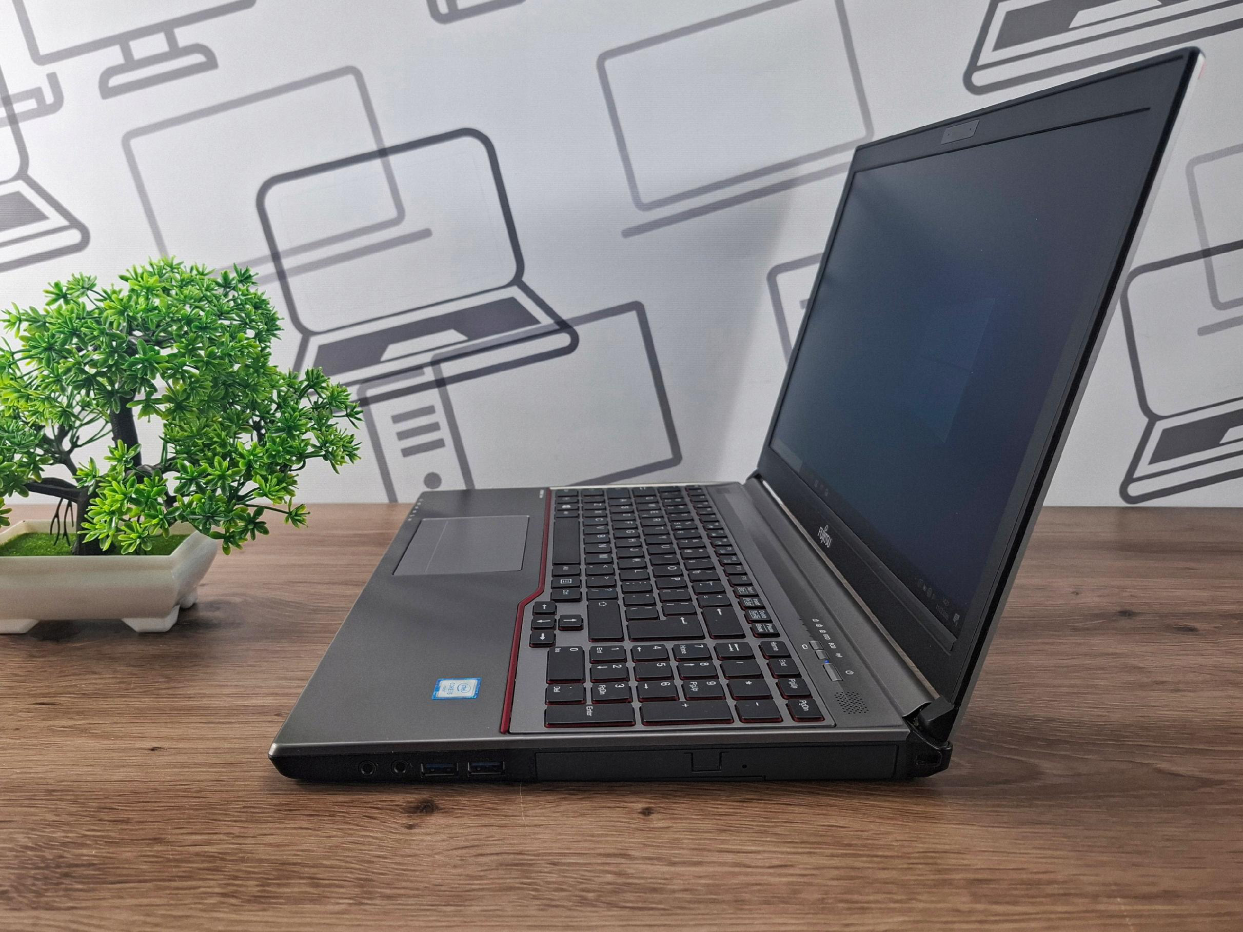 Laptop Fujitsu Lifebook otwarty pod kątem z boku, widok na klawiaturę i ciemny ekran, obudowa z widocznymi śladami użytkowania.