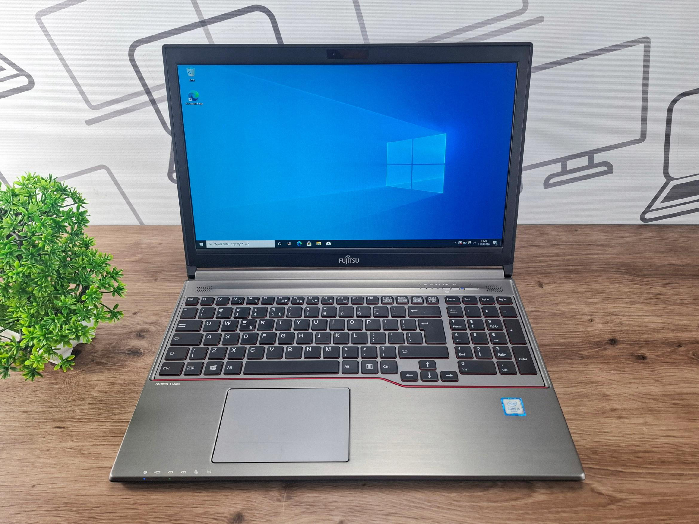 Otwarty laptop Fujitsu Lifebook z włączonym ekranem pokazującym pulpit Windows, widok z przodu pod kątem.