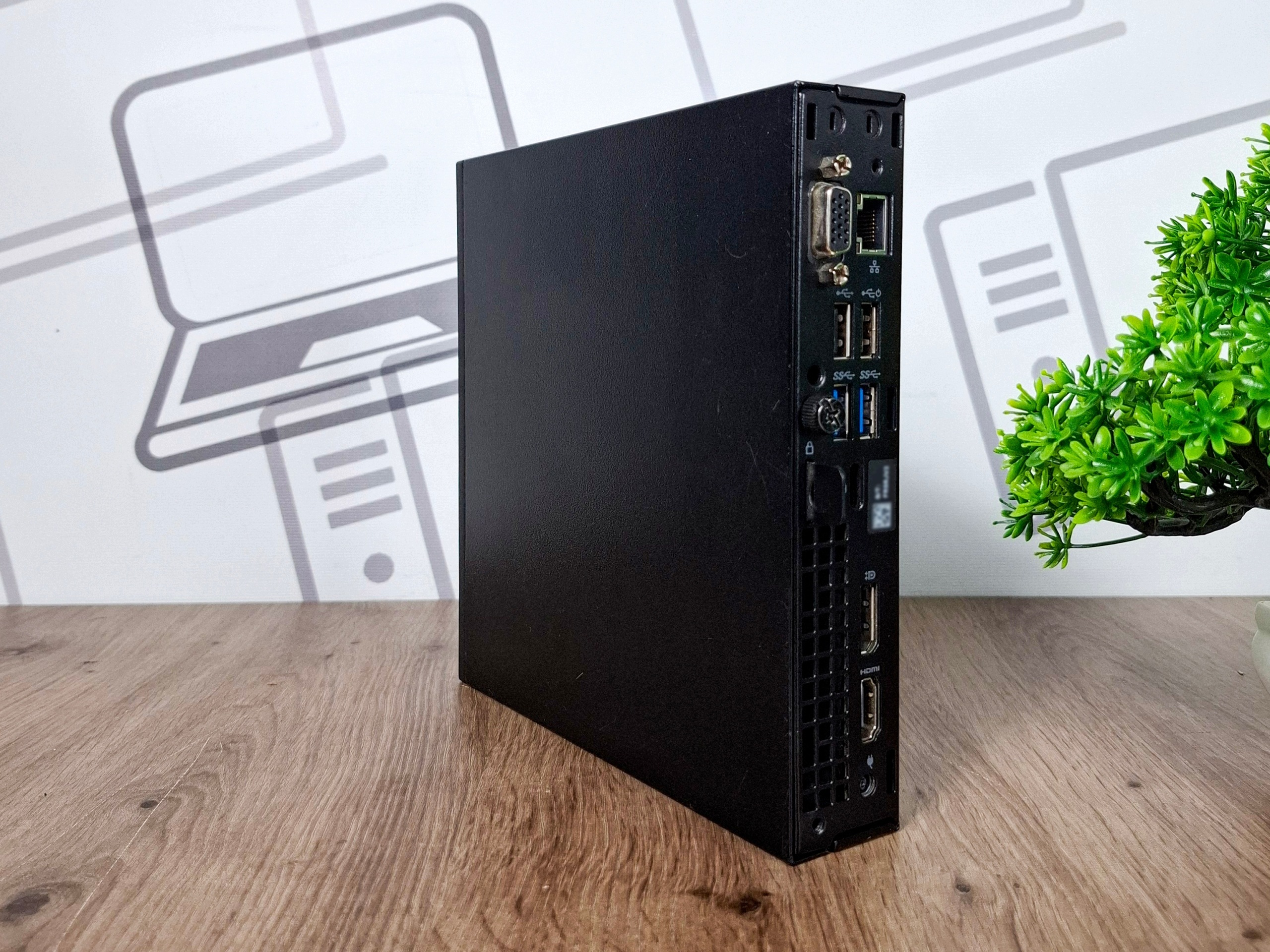 Komputer Dell Optiplex 3060 Tiny ustawiony pionowo, widok z boku na porty USB i złącza z tyłu obudowy.