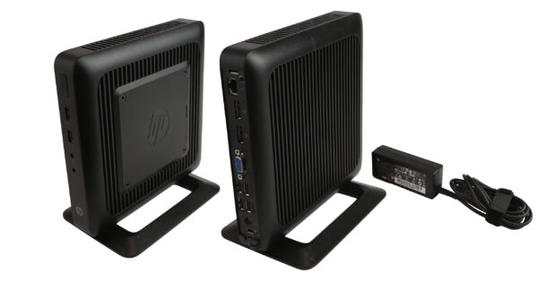 Dwa thin clienty HP t520 na podstawkach, widok z boku i z przodu, obok czarny zasilacz z kablem.