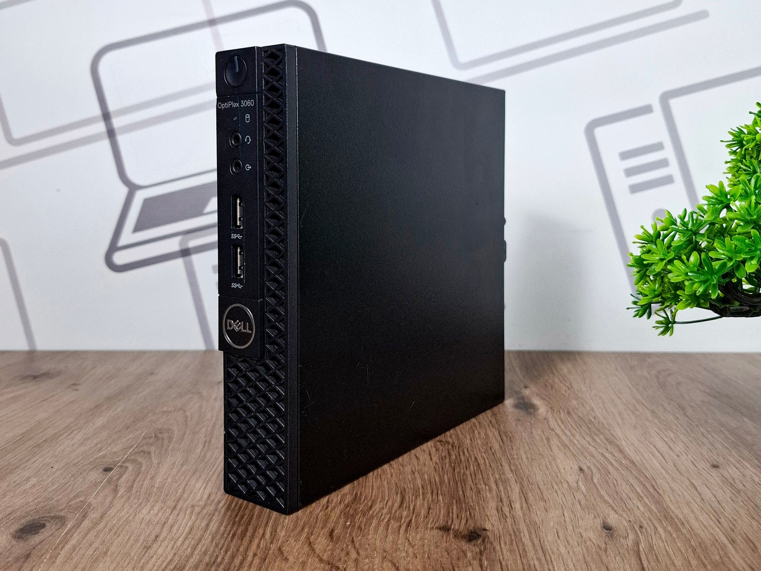 Komputer Dell OptiPlex 3060 Tiny ustawiony pionowo, widok z boku na przycisk zasilania i porty przednie.