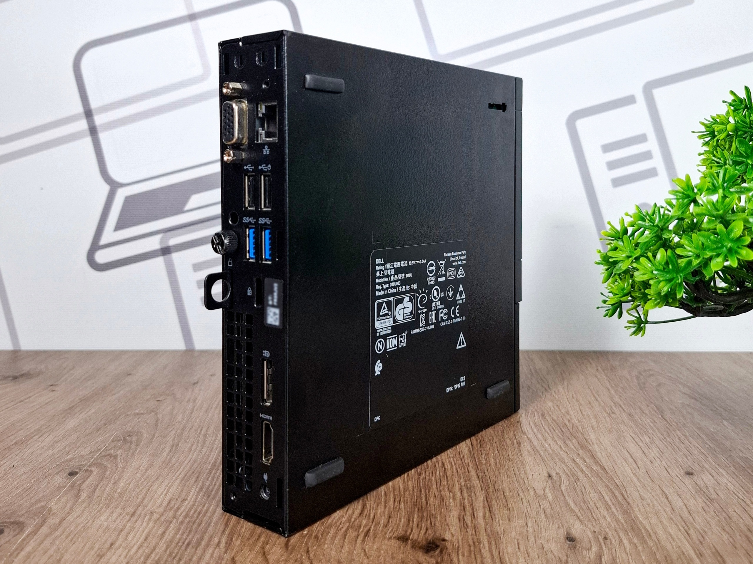 Tylny bok obudowy Dell Optiplex 3060 Tiny z portami USB, złączem zasilania i tabliczką znamionową, ustawiony na blacie.