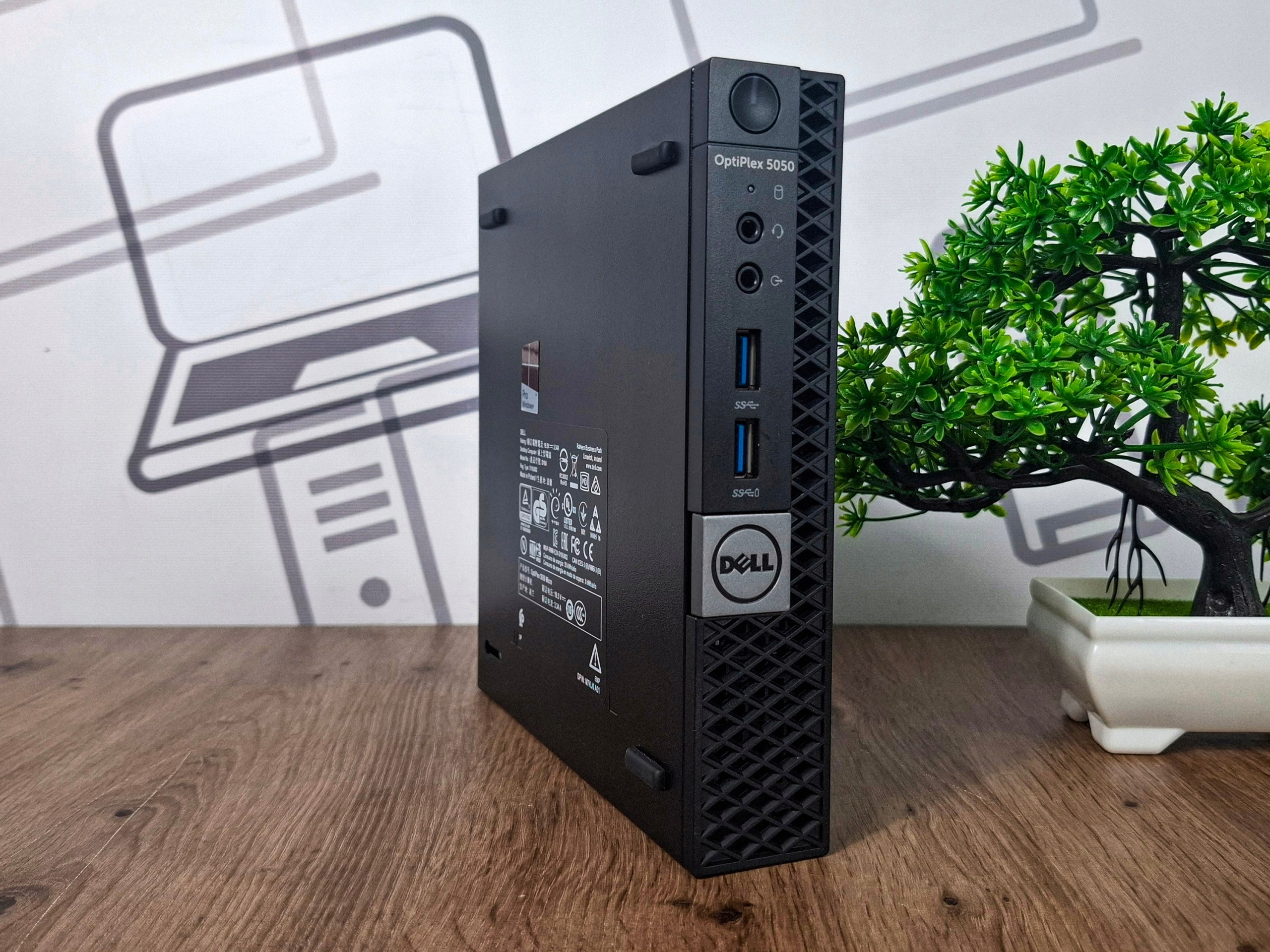 Mini komputer Dell OptiPlex ustawiony pod kątem, widoczny przycisk zasilania i porty USB oraz audio na przednim panelu.
