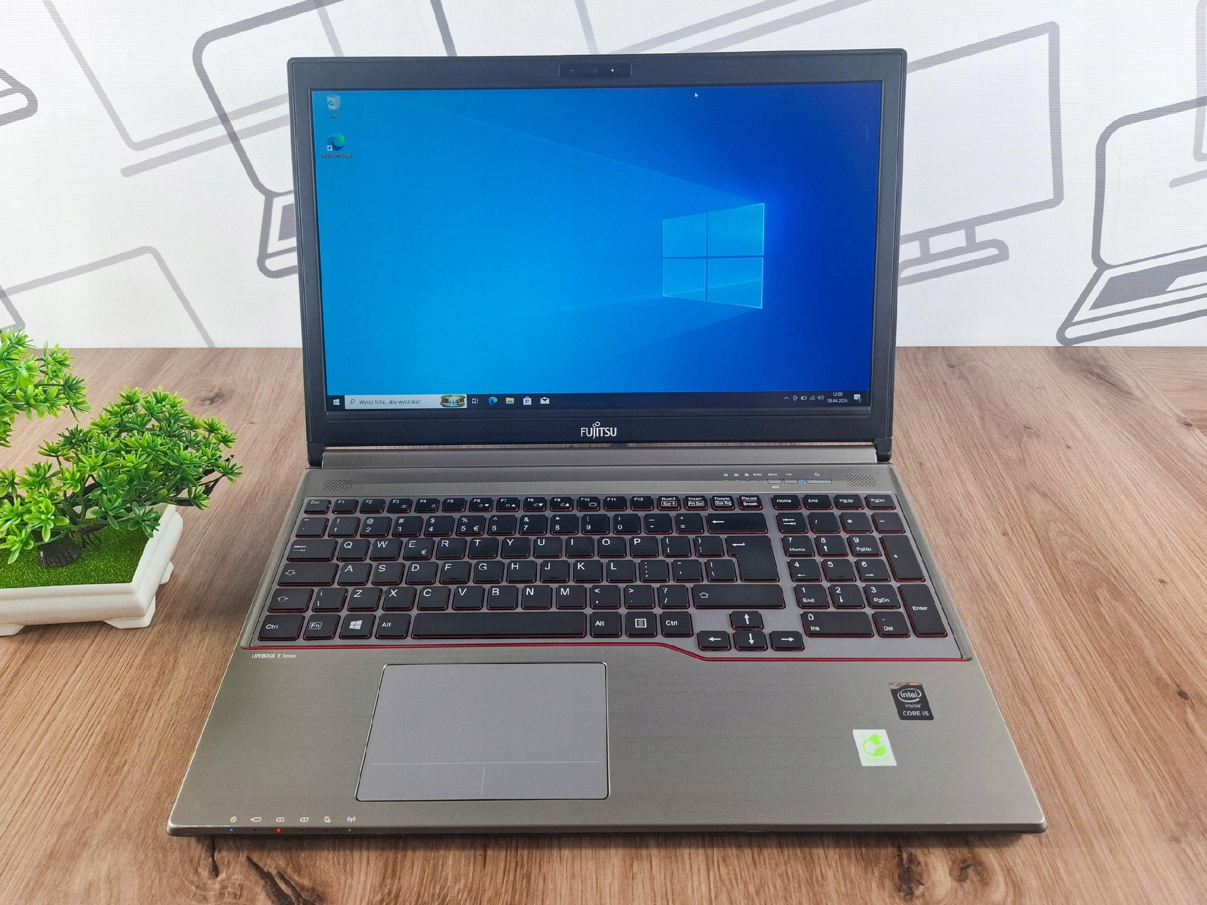 Laptop Fujitsu Lifebook otwarty pod kątem z boku, ekran z pulpitem Windows 10, widoczna klawiatura z touchpadem.