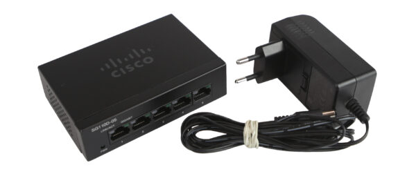 Switch Cisco SG110D-05 z przodu widoczne pięć portów RJ45, obok dołączony zasilacz sieciowy z przewodem