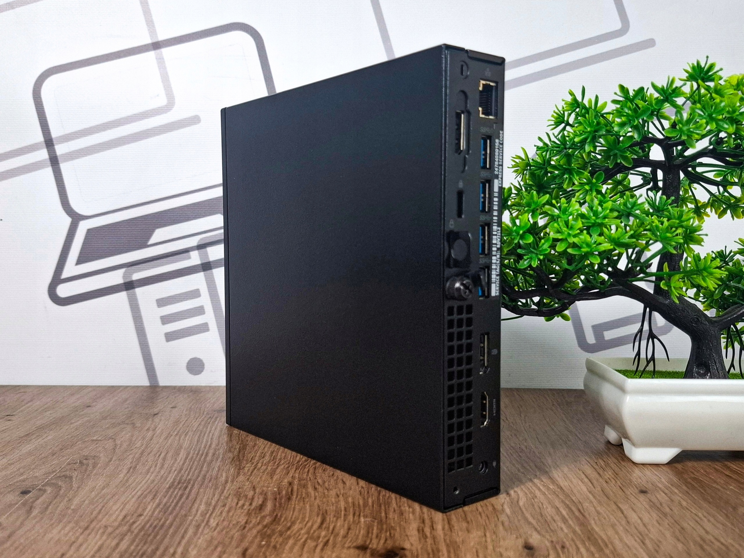 Mini komputer Dell Optiplex 5050 Tiny ustawiony bokiem, widoczna czarna obudowa i kratka wentylacyjna z otworami na śruby.
