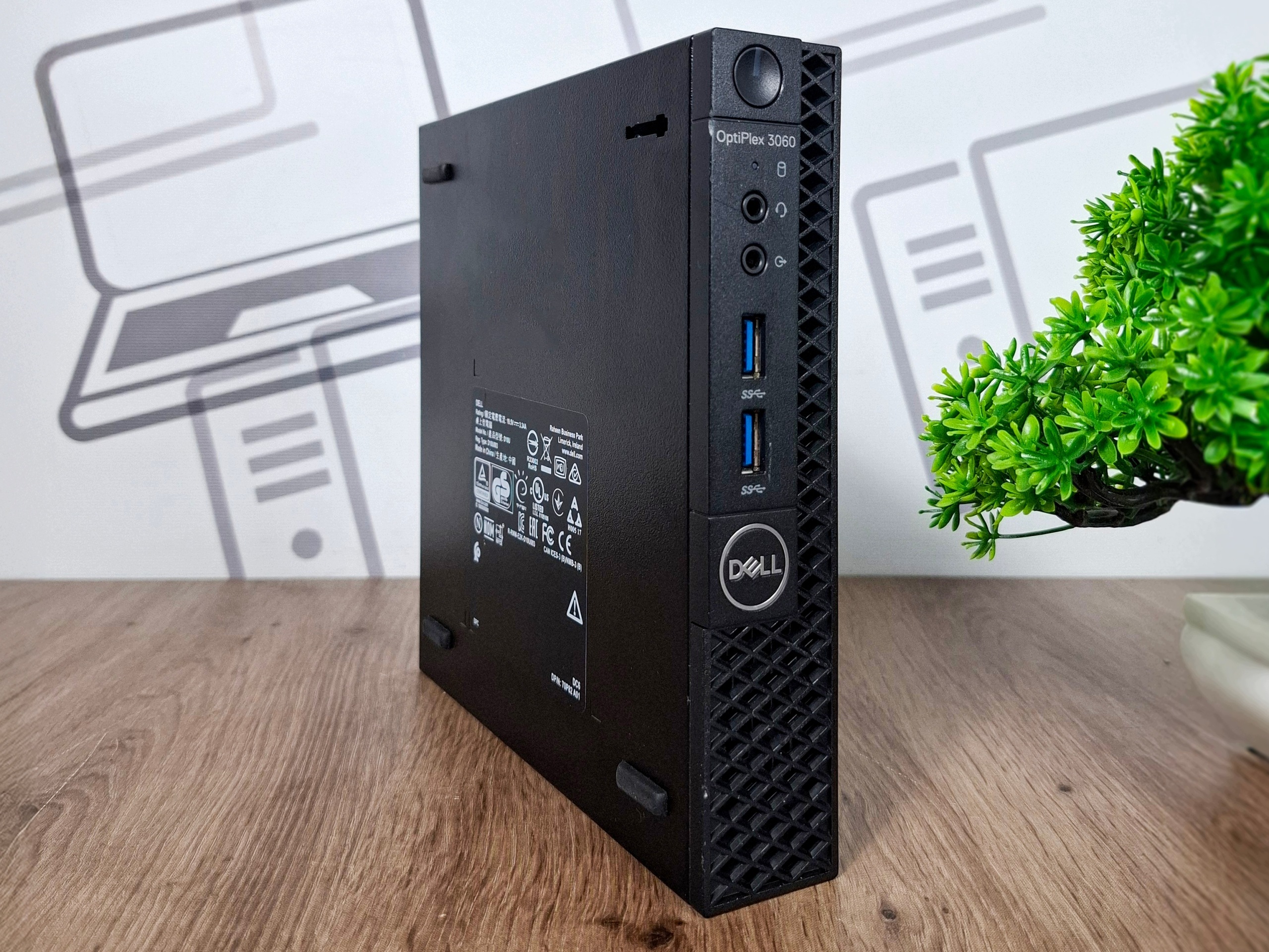 Boczny widok obudowy Dell OptiPlex 3060 Tiny z portem USB, tabliczką znamionową i logo Dell na czarnej obudowie.