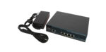 Kontroler Cisco z widocznymi czterema portami RJ45 z przodu obok dołączonego zasilacza z kablem zasilającym.