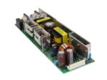 Otwarty moduł zasilacza impulsowego na płytce PCB z widocznymi kondensatorami, transformatorem i radiatorami metalowymi.