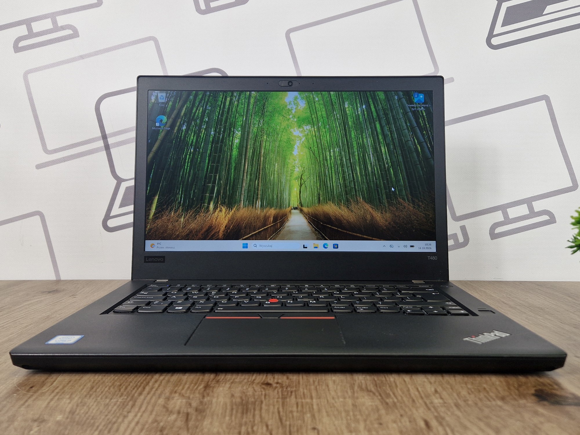 Otwarty laptop Lenovo ThinkPad T480 z włączonym ekranem, na wyświetlaczu zdjęcie leśnej ścieżki z bambusami.