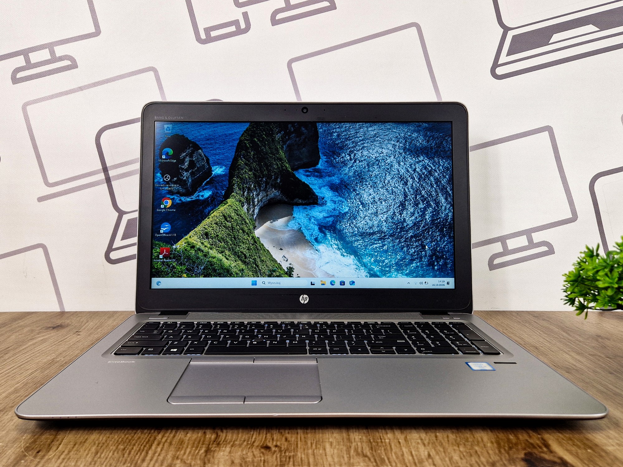 Otwarty laptop HP EliteBook 850 G3 widziany z przodu, ekran włączony z pulpitem Windows i widokiem gór.