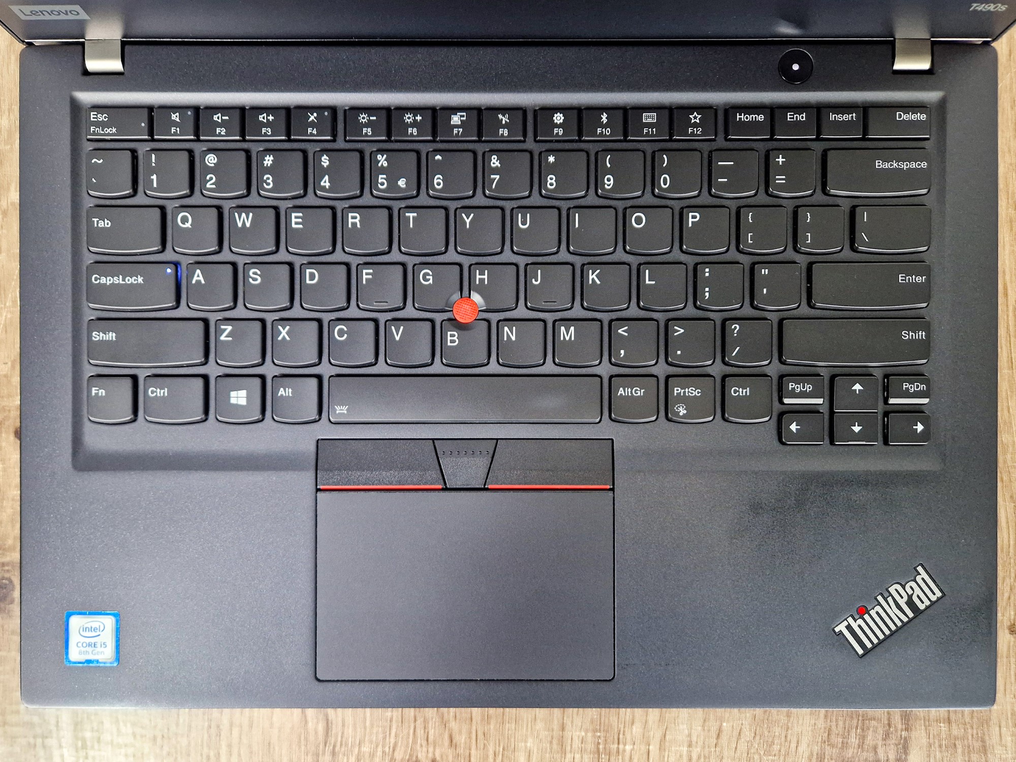 Widok z góry na klawiaturę laptopa Lenovo ThinkPad z czerwonym TrackPointem i touchpadem z przyciskami.