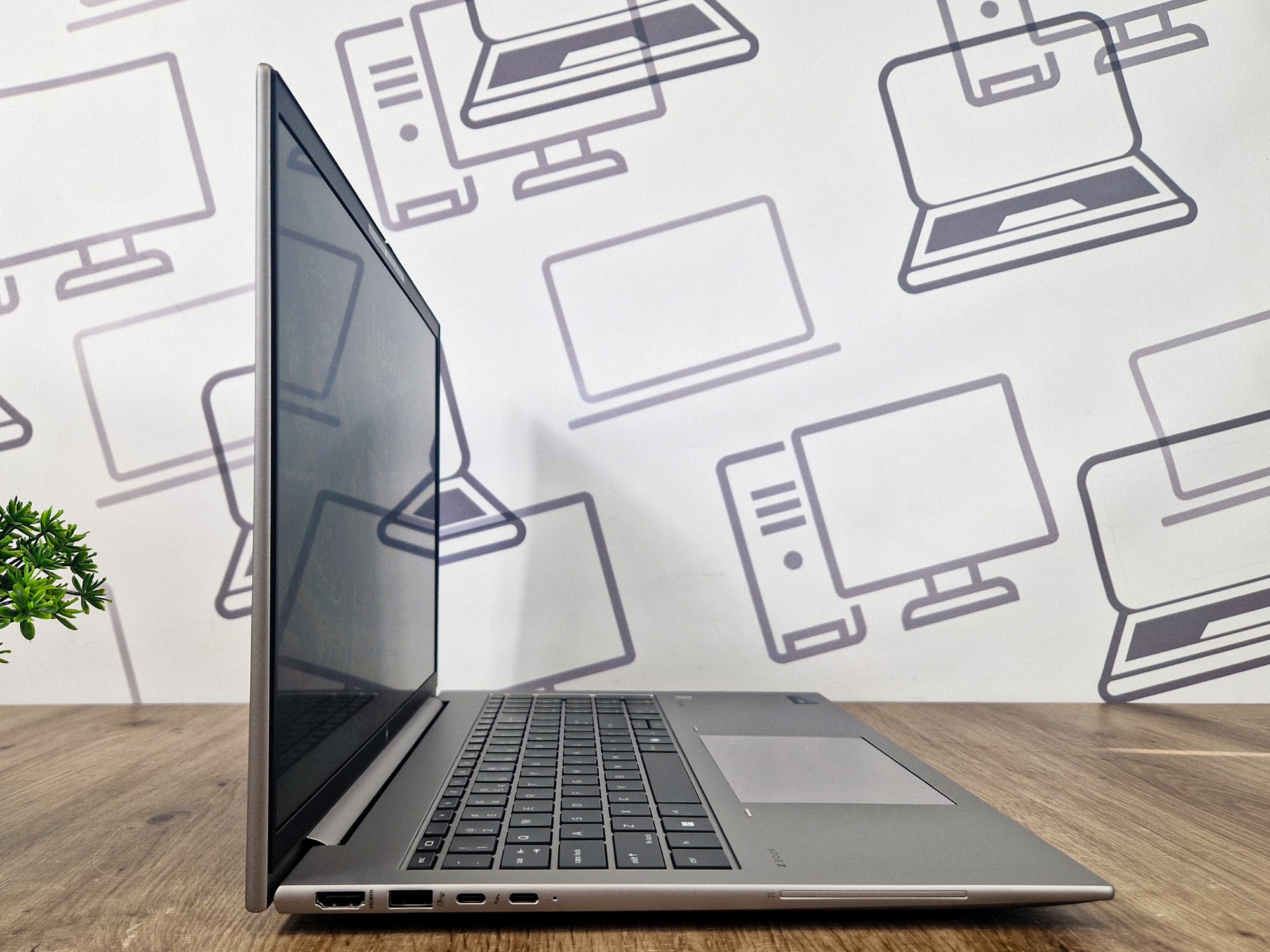 Laptop HP Zbook Firefly otwarty pod kątem z boku, widoczne porty USB-C po lewej stronie obudowy, ekran wyłączony.