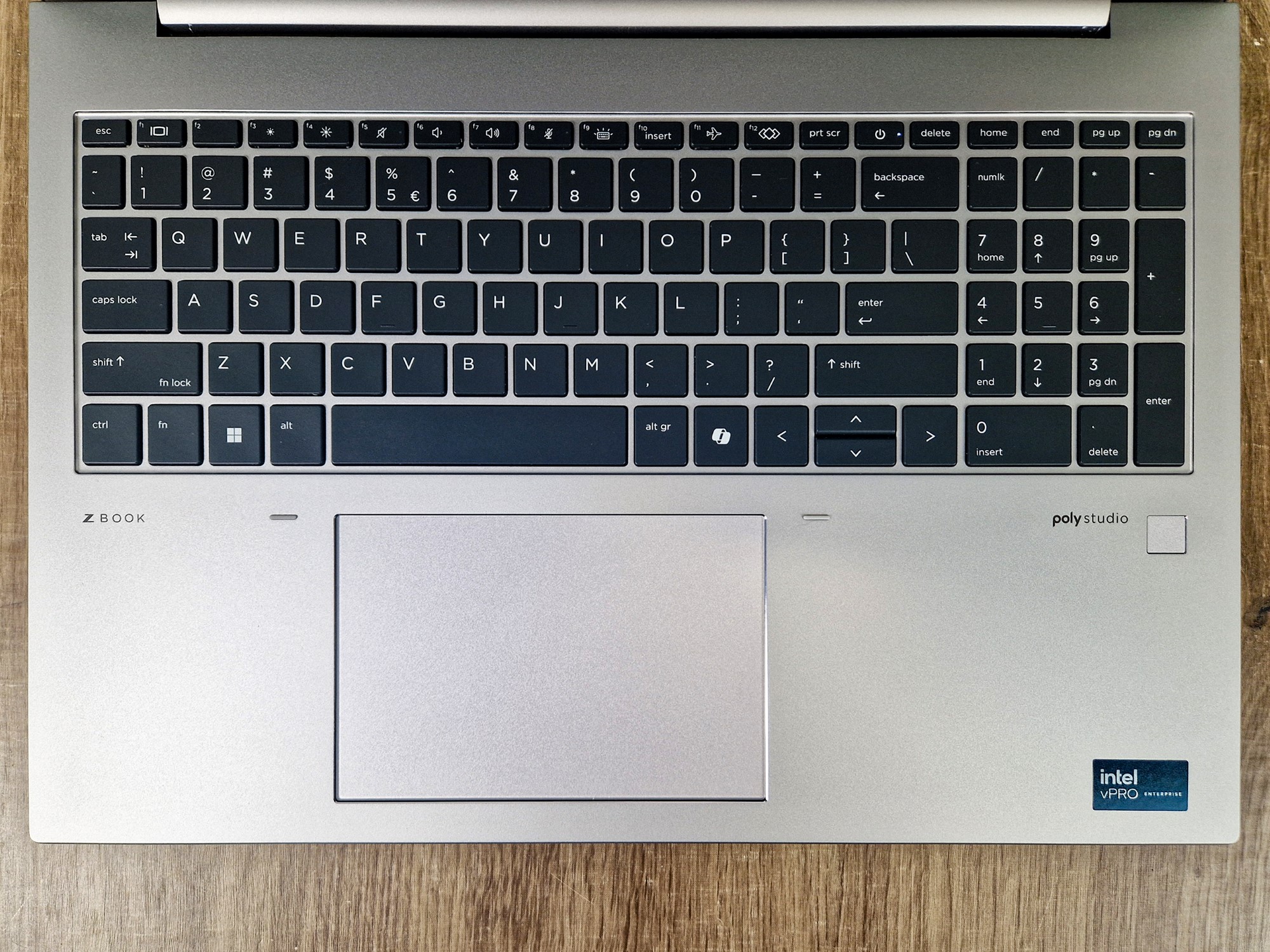 Widok z góry na klawiaturę laptopa HP ZBook Firefly z podświetleniem, gładzikiem i naklejkami Intel oraz Poly Studio.