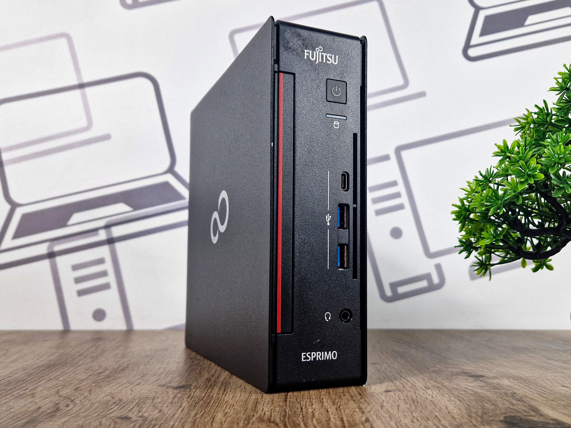 Obudowa Fujitsu Esprimo Q7010 typu mini PC ustawiona pionowo, widok z przodu pod kątem z czytnikiem kart i przyciskiem zasilania.