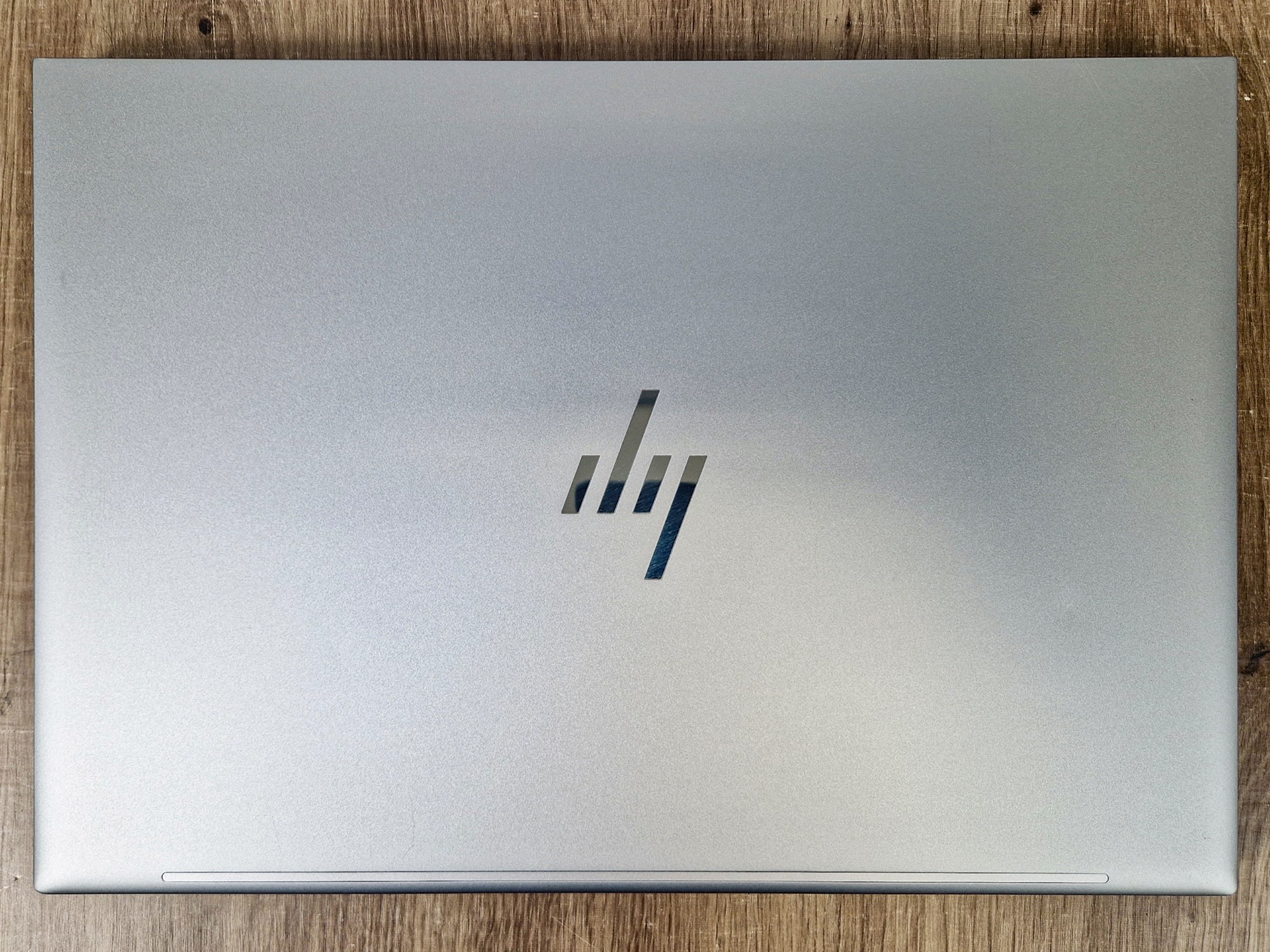 Zamknięta pokrywa laptopa HP w srebrnym kolorze z widocznym logo HP na środku, zdjęcie z góry.