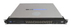Przedni panel switcha Cisco Linksys SR2024 z 24 portami RJ45 i dwoma slotami SFP, uszy montażowe po bokach.